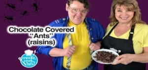 Two people smile as they show chocolate-covered raisins.
