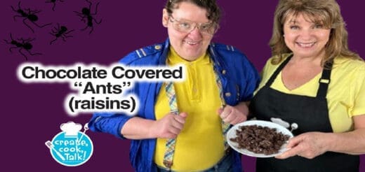 Two people smile as they show chocolate-covered raisins.