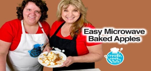 Two women smile while holding a plate of baked apples.