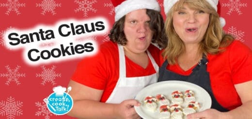 Two people in Santa hats hold a plate of Santa Claus cookies.