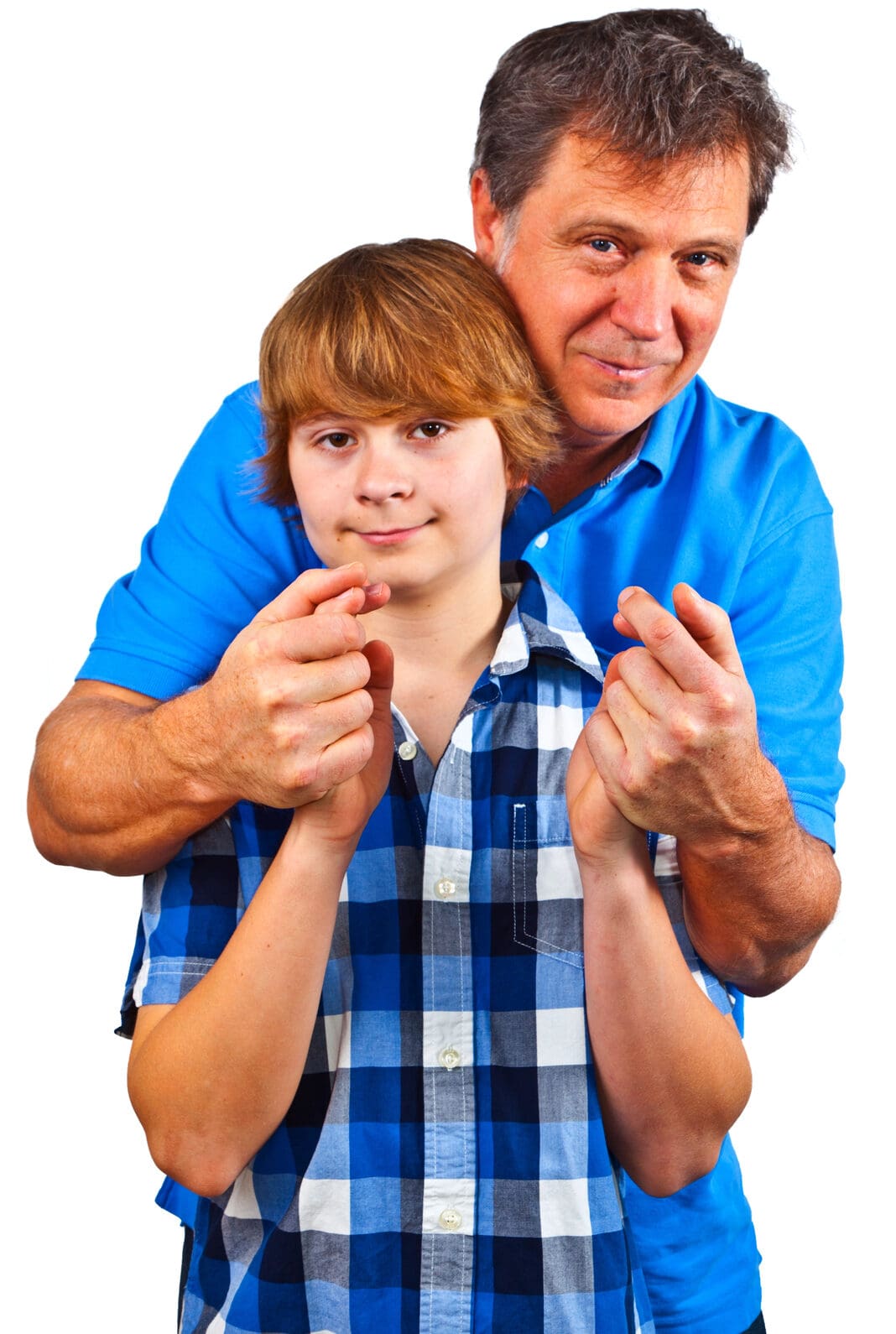 An adult standing behind and embracing a youth, both holding their hands together in front of them.