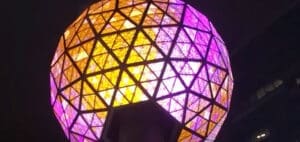 Geodesic dome illuminated with purple and orange lights at night.