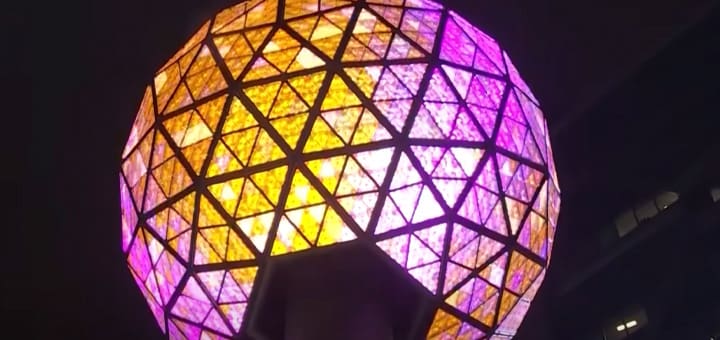 Geodesic dome illuminated with purple and orange lights at night.