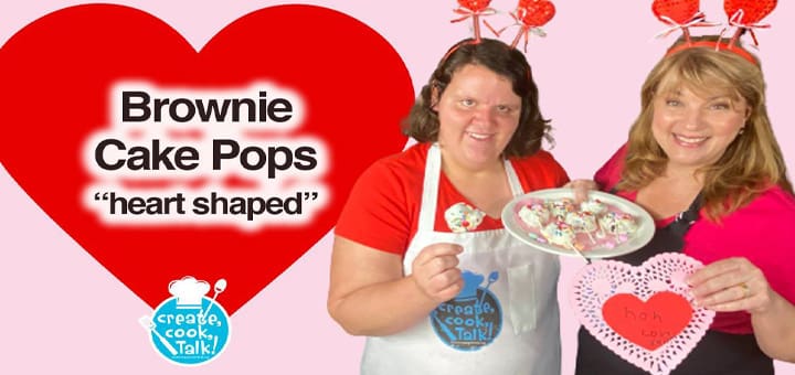 Two women hold brownie cake pops and heart decorations.