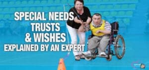 A woman assists a man in a wheelchair with an orange cone in the foreground.