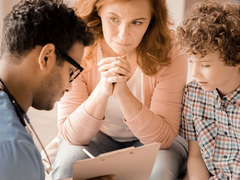 Doctor, woman, and child look at a clipboard.