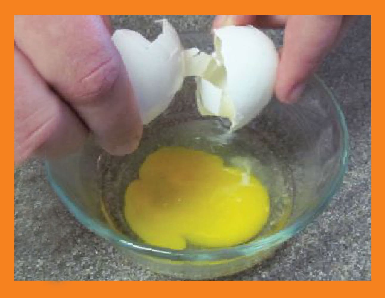 Hands cracking an egg into a glass bowl.