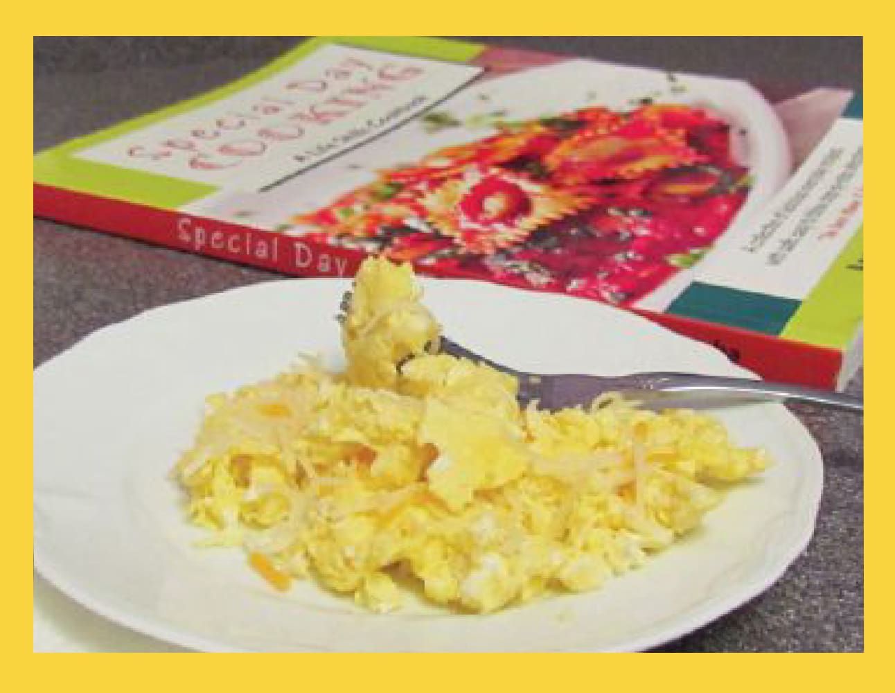 Plate of scrambled eggs with a cookbook titled "Special Day Cooking" in the background.
