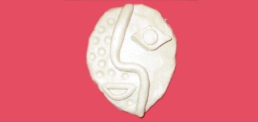 White abstract clay face with circular indentations and a wavy line across the center.