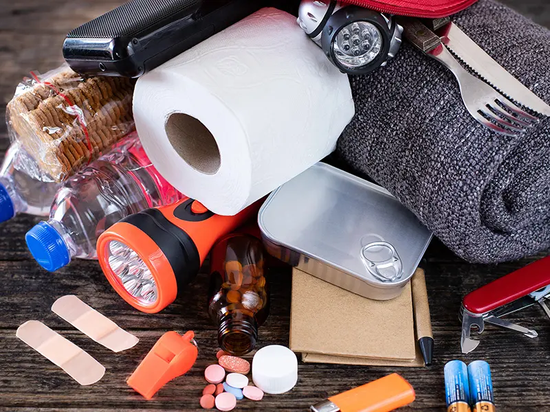 Emergency kit items including a flashlight, toilet paper, canned food, and water bottles