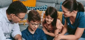 Family looking down at something together on a couch.