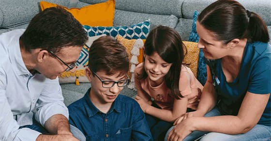 Family looking down at something together in a living room setting.