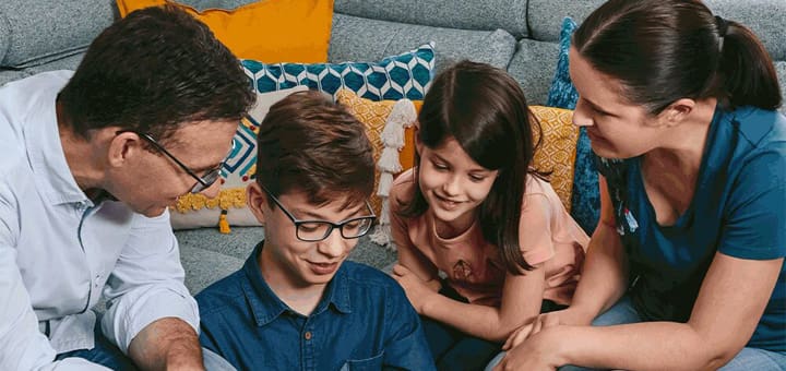 Family looking down at something together on a couch.