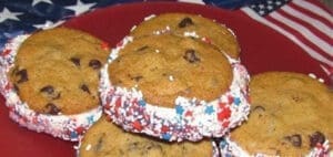 Ice cream sandwiches with red, white, and blue sprinkles on a plate with an American flag in the background.