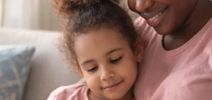 Woman hugging a young child, both smiling.