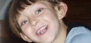 A young boy smiles, showing missing teeth.