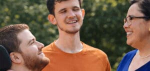 Three people smiling and interacting outdoors during a conversation about supported decision-making.
