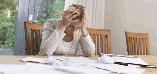 Woman with hands on head at table with papers