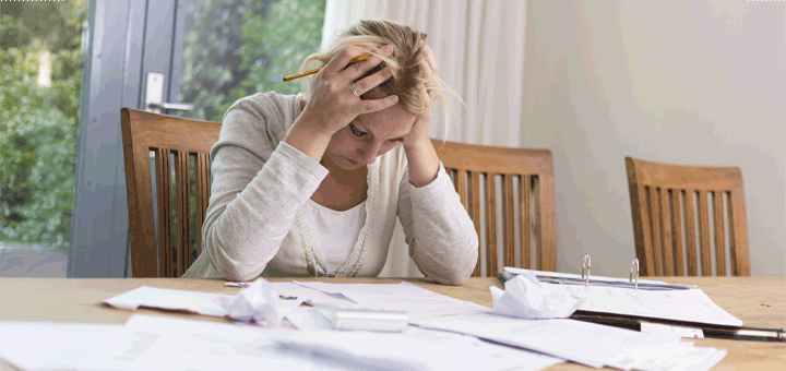 Woman with hands on head at table with papers