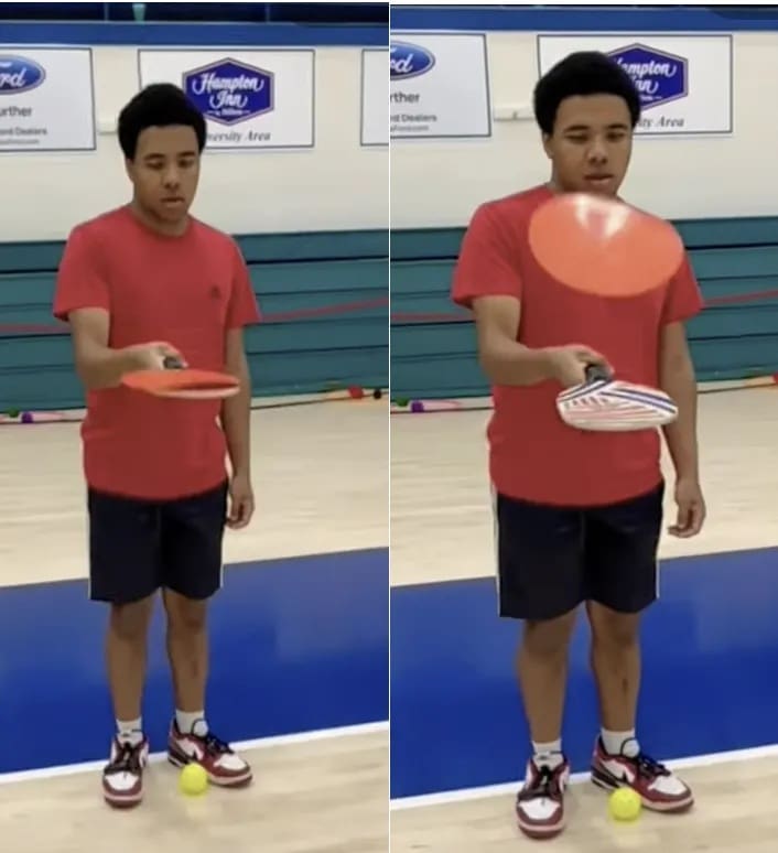 Two young men in red shirts and blue shorts stand side-by-side on a court holding objects.