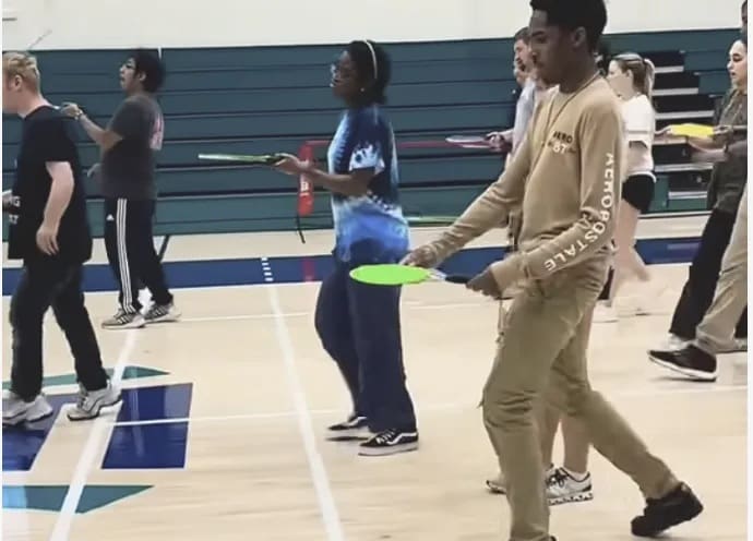 Young people practice pickleball skills on an indoor court.