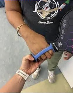 Two hands grasp a pickleball paddle handle, one assisting the other.